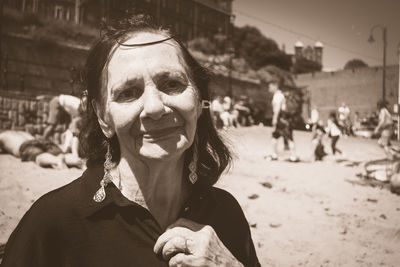 Portrait of mature woman standing at beach during sunny day