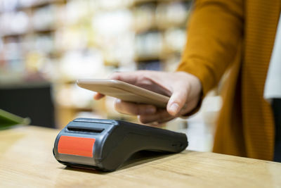 Young woman paying at checkout of grocery store using smart phone