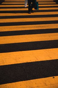 Low section of man walking on zebra crossing