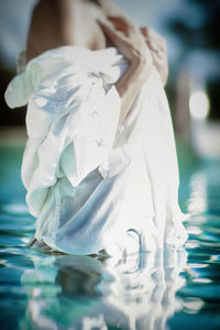 Midsection of seductive woman standing in swimming pool