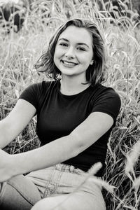 Portrait of smiling young woman sitting on field