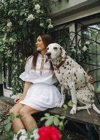 Portrait of woman with dog sitting on bench on street