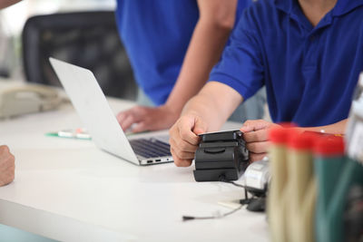 Midsection of man using mobile phone on table