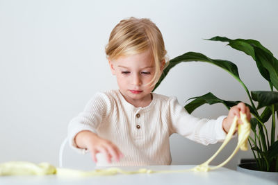 Portrait of cute girl playing with slime against white background