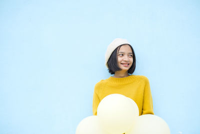 Smiling young woman standing against blue background