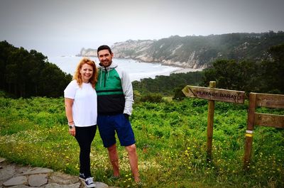 Portrait of couple standing on field against mountains