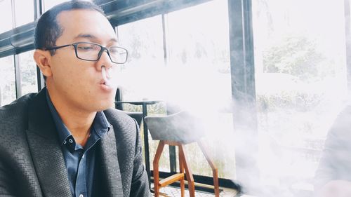 Businessman vaping by window