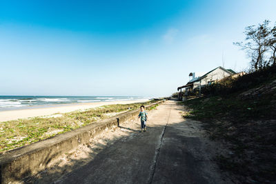 Man on road by sea against clear sky