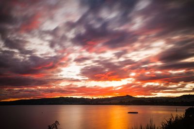 Scenic view of beach against cloudy sky during sunset