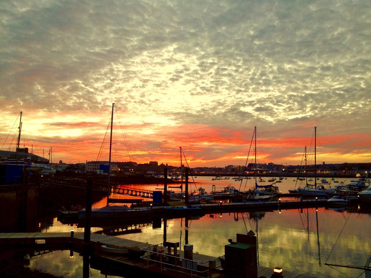 BOATS MOORED IN HARBOR AGAINST SKY DURING SUNSET