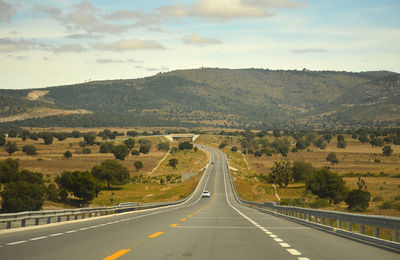 Road passing through landscape against sky