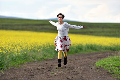 Young man running on field against sky