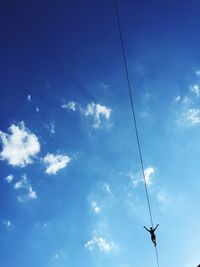 Low angle view of silhouette person balancing on slackline against blue sky