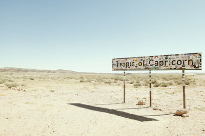 Information sign on desert against clear sky