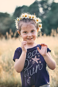 Portrait of smiling girl wearing flowers while standing on land