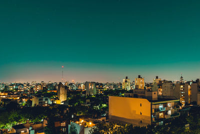 High angle view of illuminated buildings against clear blue sky