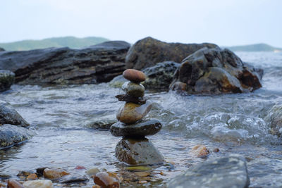 Stack of stones at beach against sky