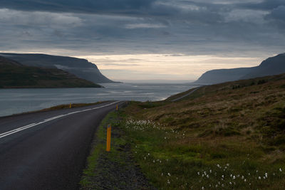 Road by sea against sky during sunset