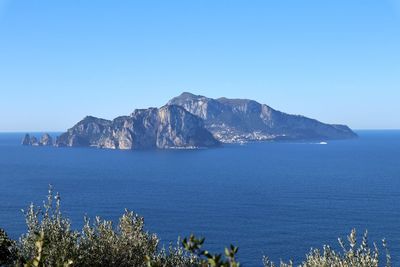 Scenic view of sea and mountains against clear blue sky