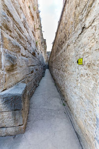 Narrow footpath amidst wall