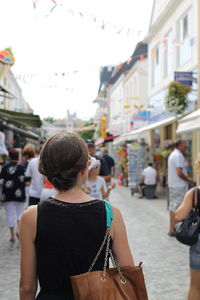 Rear view of woman walking towards people in street market