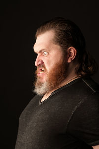 Portrait of man looking away against black background