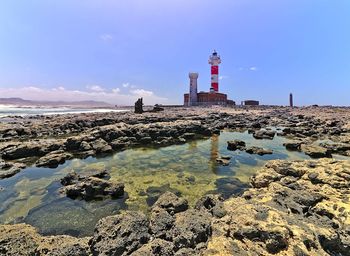 Lighthouse by sea against sky