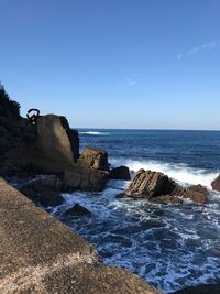 Rocks on beach against blue sky