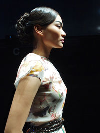 Side view of a young woman looking away over black background