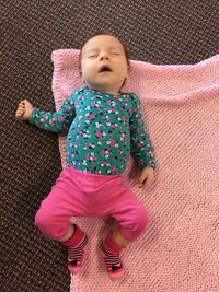 Directly above view of baby girl sleeping on pink blanket at home