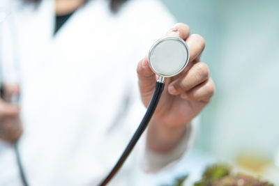 Midsection of doctor holding stethoscope at hospital