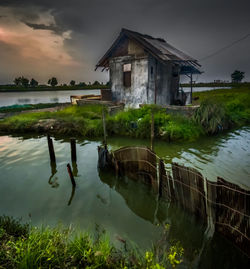 Abandoned house by lake against sky