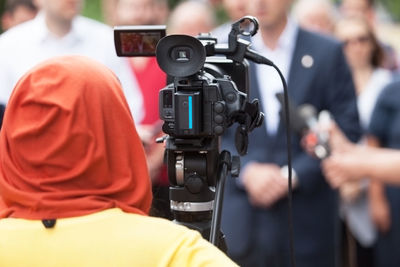 Rear view of female journalist filming people during interview
