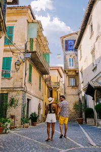 Rear view of people walking on street amidst buildings in city