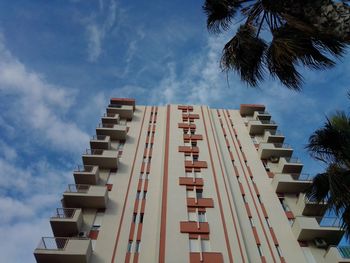 Low angle view of palm trees and building against sky