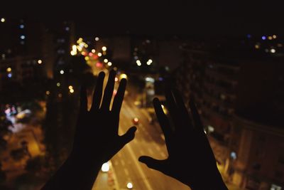 Close-up of silhouette hands above illuminated street at night