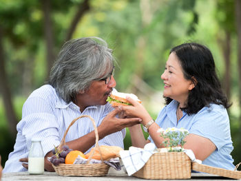 Mature couple having breakfast at table during picnic
