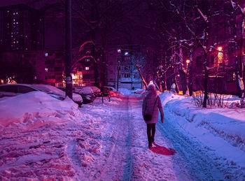 Rear view of woman walking on snow covered street