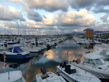 Sailboats moored on harbor in city against sky