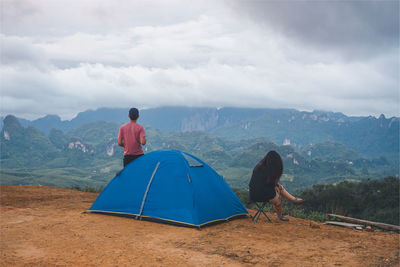 Rear view of man looking at mountains against sky