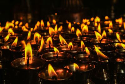 Close-up of lit diyas in temple