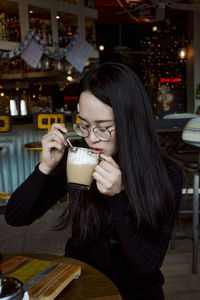 Young woman drinking drink at restaurant