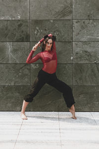 Full length of woman dancing on floor against wall