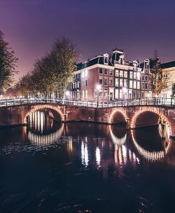 Bridge over river in city at night