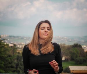 Beautiful young woman standing against sky