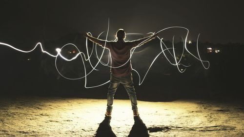 Rear view of man with light painting while standing on ground