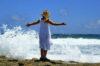 Full length of woman with arms outstretched on beach