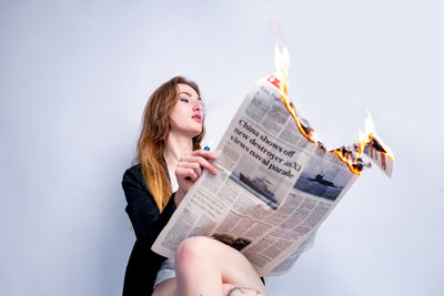 Midsection of woman reading book while sitting at home