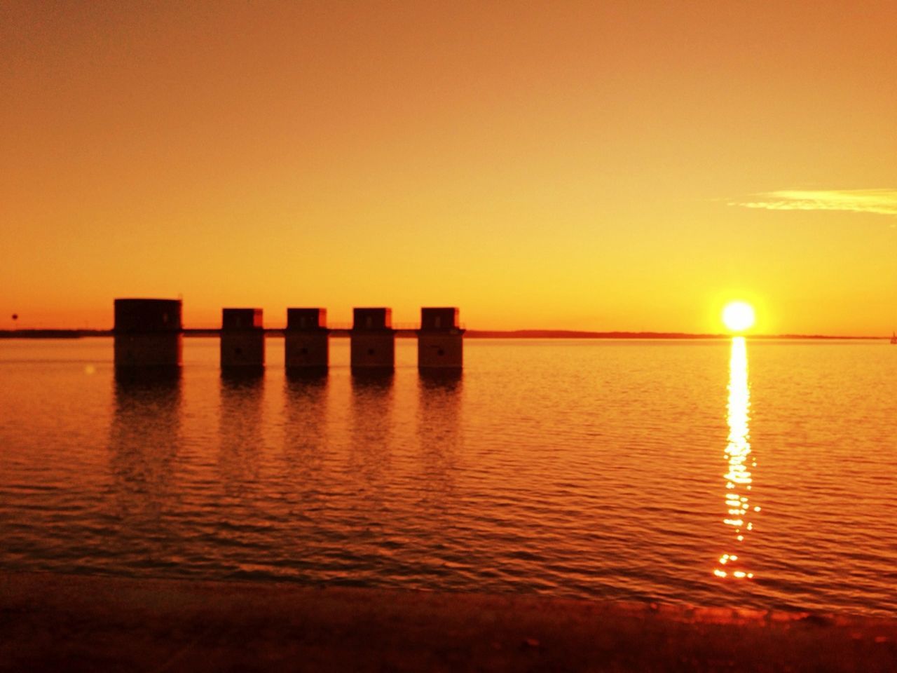 sunset, water, sea, reflection, scenics, tranquil scene, orange color, tranquility, sun, waterfront, beauty in nature, idyllic, horizon over water, nature, silhouette, wooden post, sky, clear sky, copy space, rippled