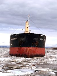 Abandoned ship on beach against sky